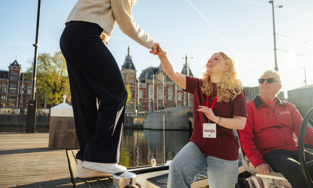 Two young women on a city trip to Amsterdam. A woman helps another up.