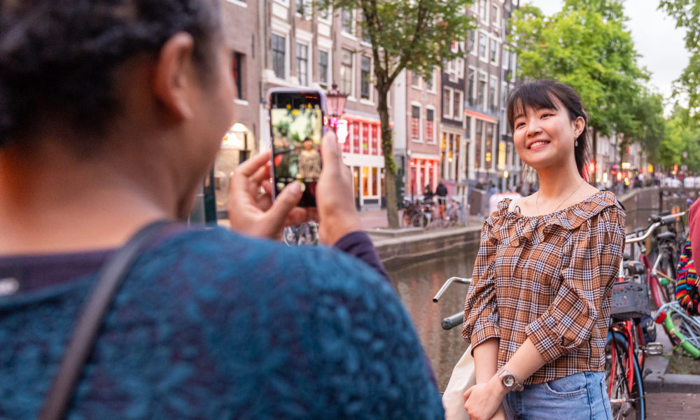 Woman smiling at camera in Amsterdam. Colourful buildings in the background.