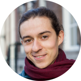 A smiling woman wearing a scarf. She appears to be in Amsterdam.