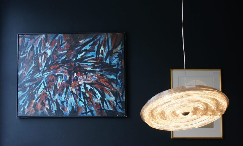 A modern pendant light next to a blue and red painting. Unique Amsterdam interior design.