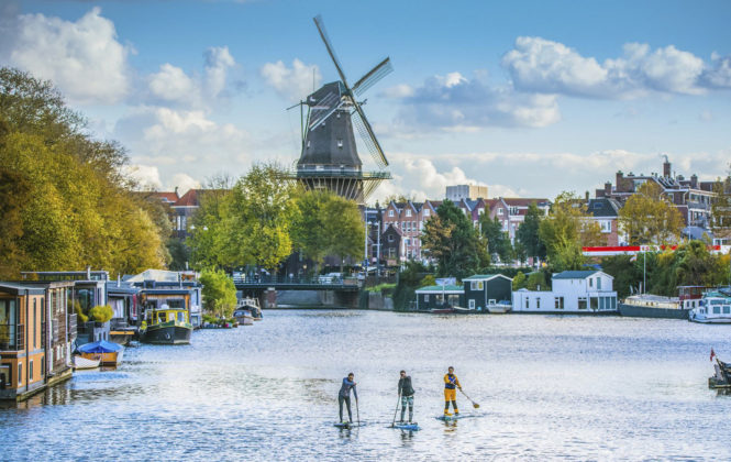 Stand up paddling in Amsterdamer Fluss während Firmenreise in Amsterdam