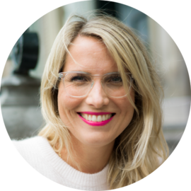 A smiling woman with blonde hair and glasses