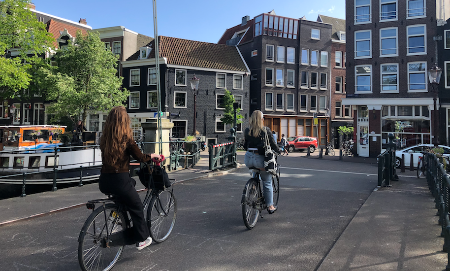 Dos mujeres en bicicleta sobre un puente en Ámsterdam