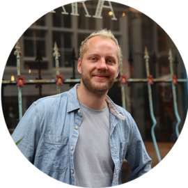 Man smiling in front of a fence.