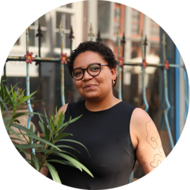 A woman with dark hair and glasses in Amsterdam. She is smiling and looking at the camera.