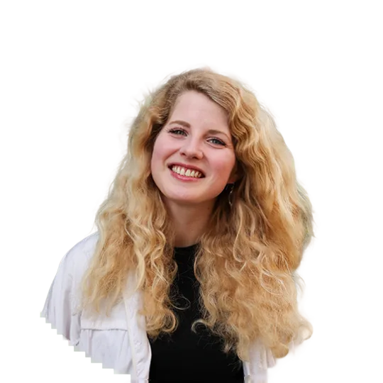 A smiling blonde woman on a city trip. She has long, curly hair.
