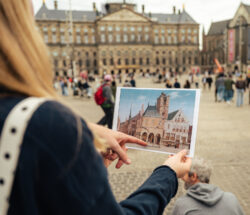 A tourist comparing a photo with a real building. Amsterdam city trip.